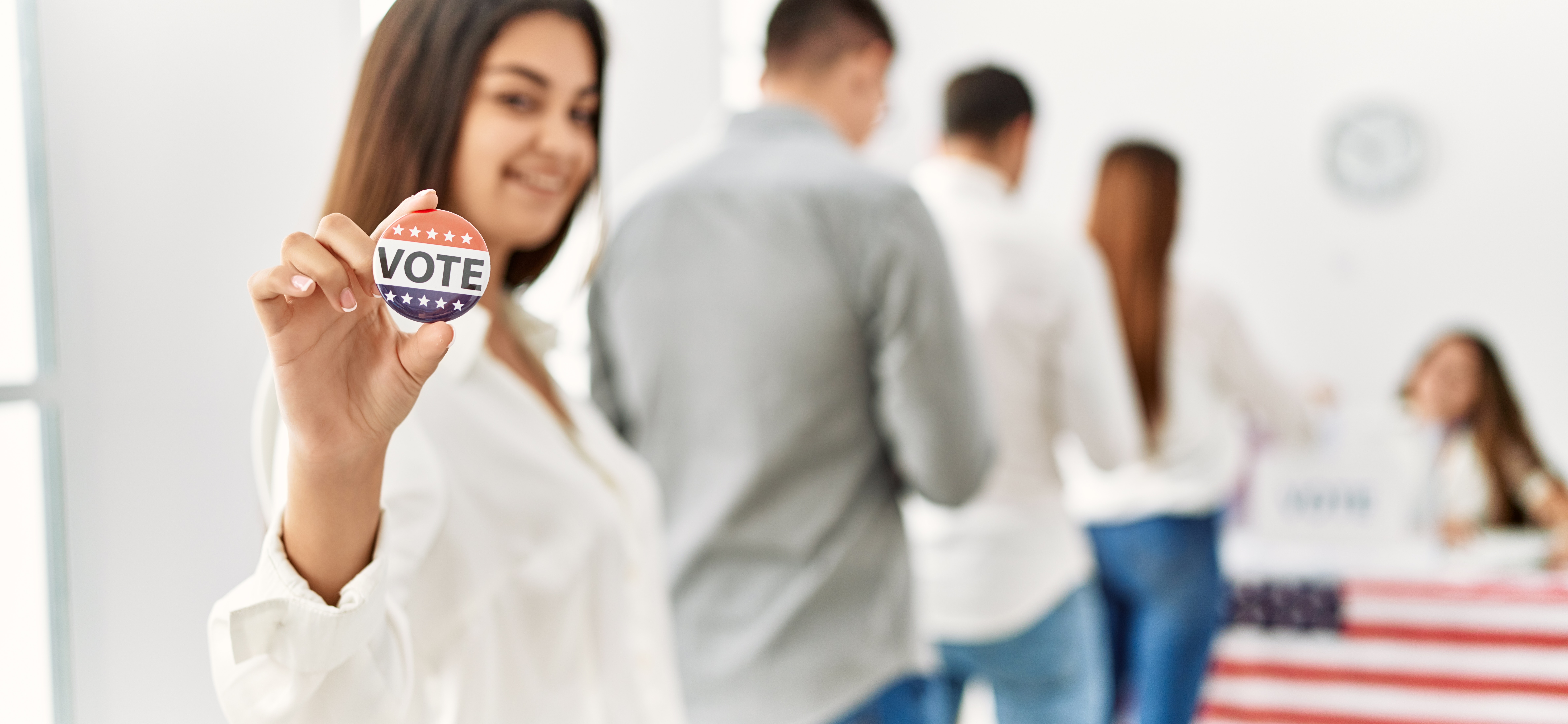 female voter at a polling place with a button that says Vote