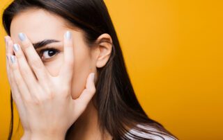 Woman with hand over face to represent hiding domestic violence