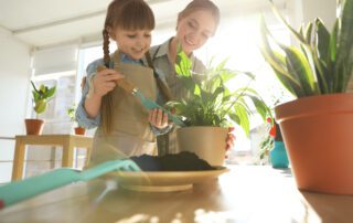 mother teaching daughter about home plants in summer